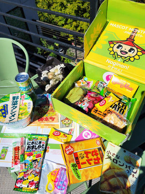 An image of the Noginon Mix with some of the snacks and candies laid out on a table around it.